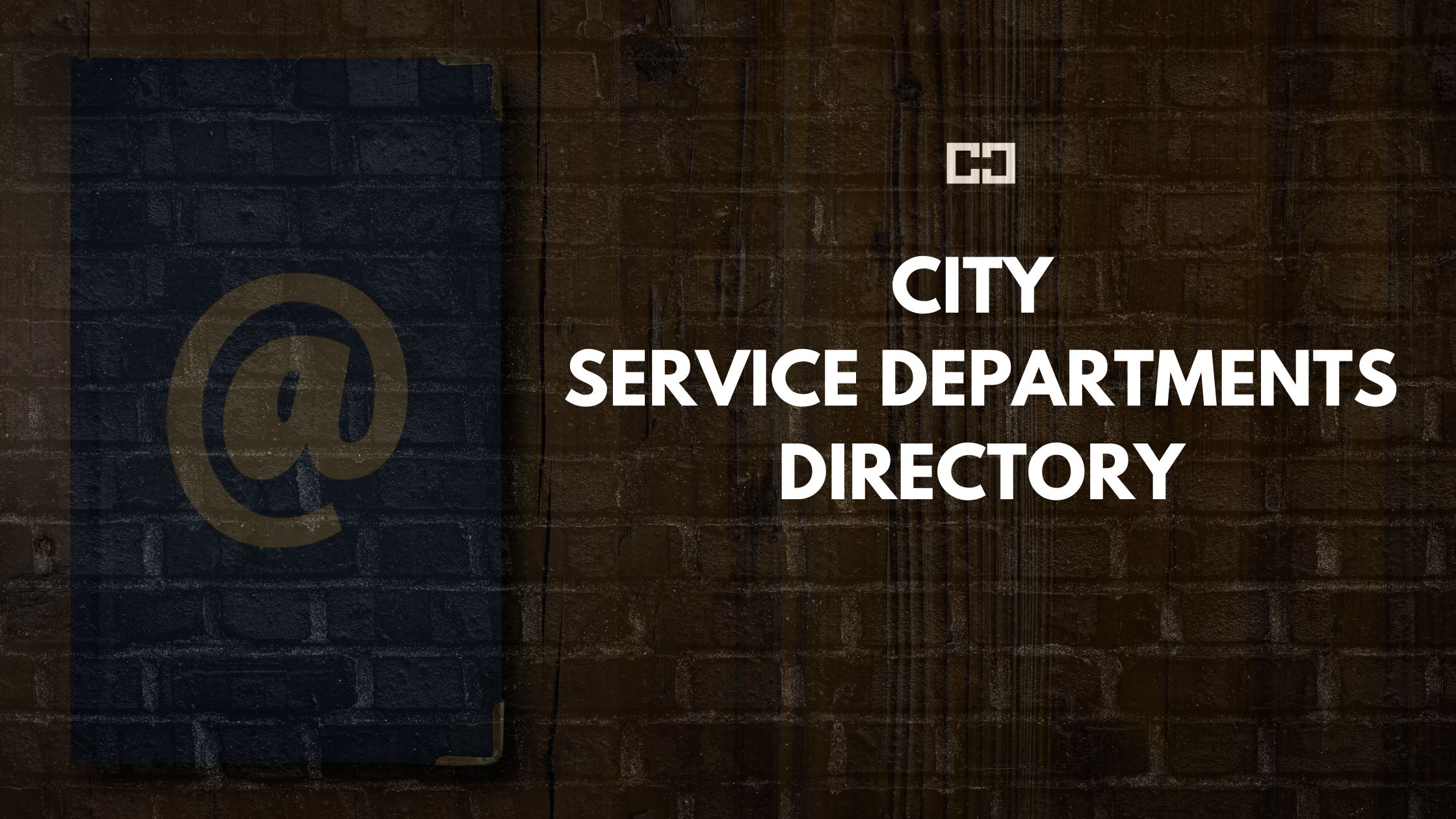 City Service Departments Directory text displayed on a dark brick wall background with a prominent '@' symbol.
